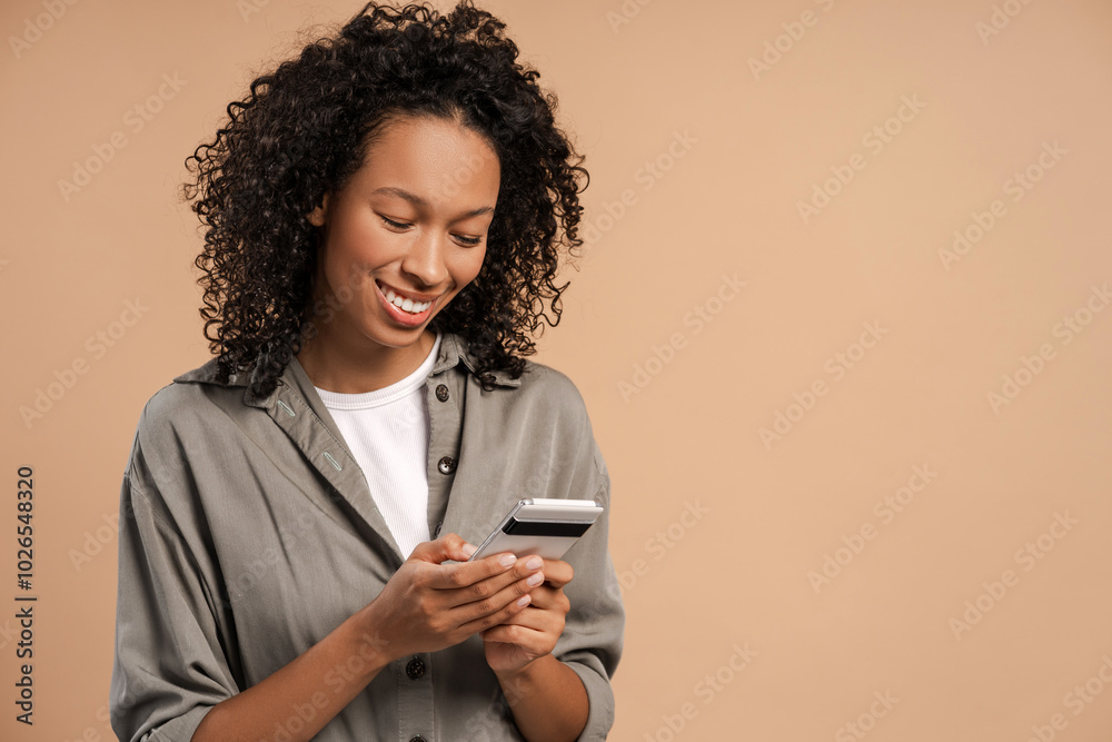 Happy African American woman reading message on smartphone isolated on beige Happy African American woman reading message on smartphone isolated on beige