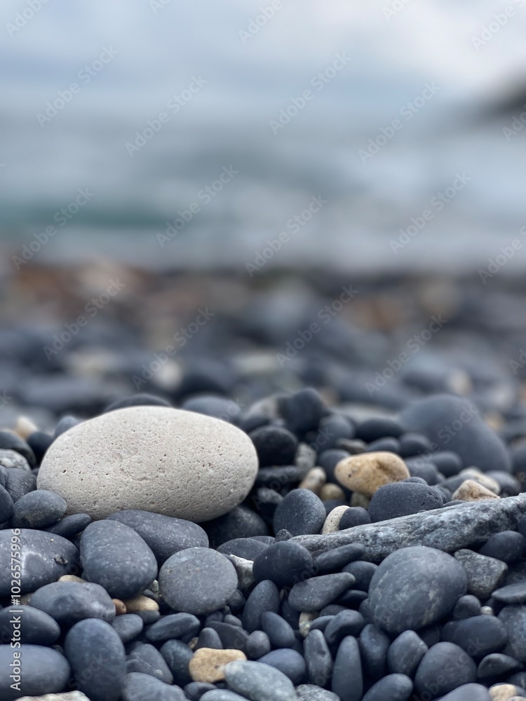 white round stone on the seashore with black sand white round stone on the seashore with black sand