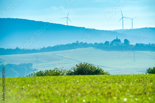 Windräder im Untertaunus bei Bad Camberg mit der bekannten Kreuzkapelle und Feldern im Vordergrund photo