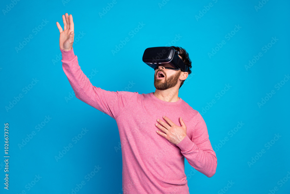 Naklejka premium Astonished young man experiencing virtual reality with VR headset against vibrant blue background