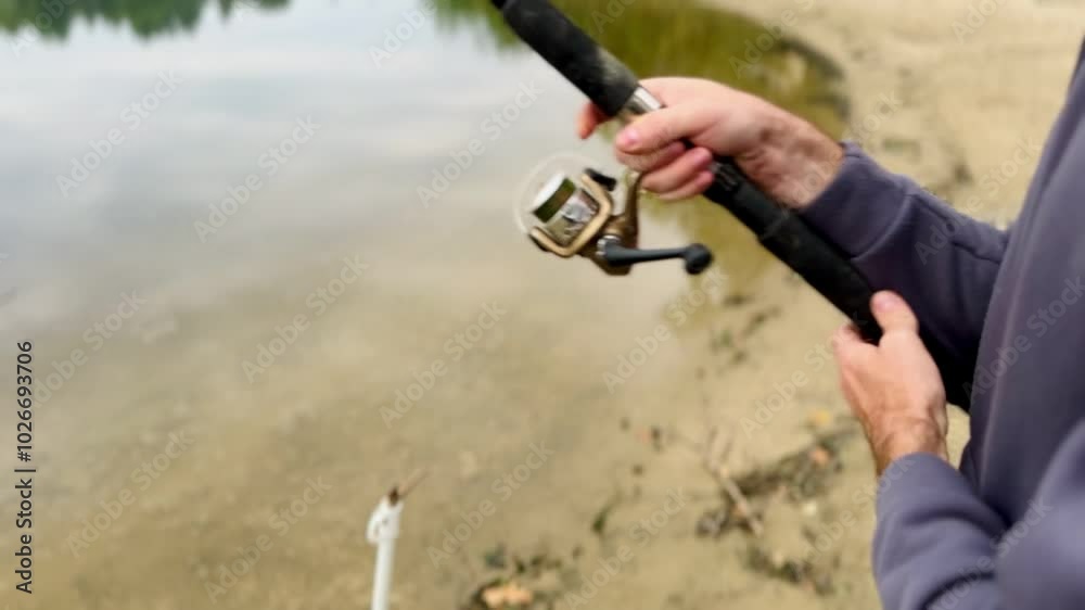 Fishing, a fisherman shows how a reel on a fishing rod works Fishing, a fisherman shows how a reel on a fishing rod works