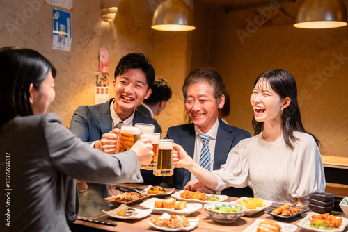 居酒屋で乾杯をする男女のビジネスパーソン