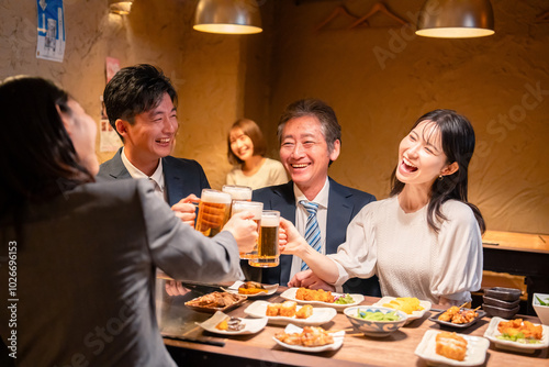 居酒屋で乾杯をする男女のビジネスパーソン