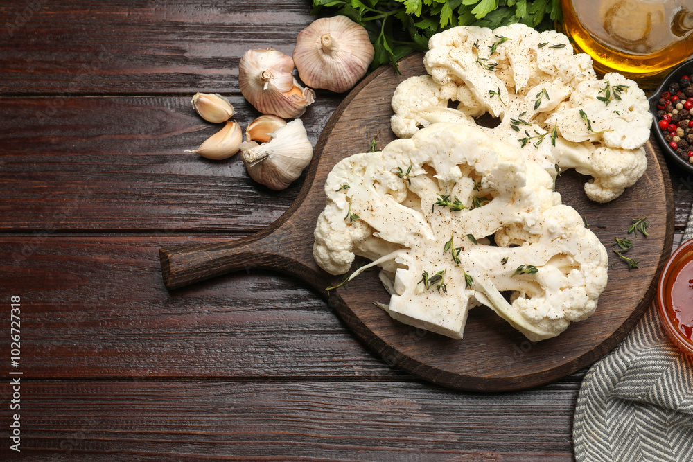Uncooked cauliflower steaks, oil and spices on wooden table, flat lay Uncooked cauliflower steaks, oil and spices on wooden table, flat lay