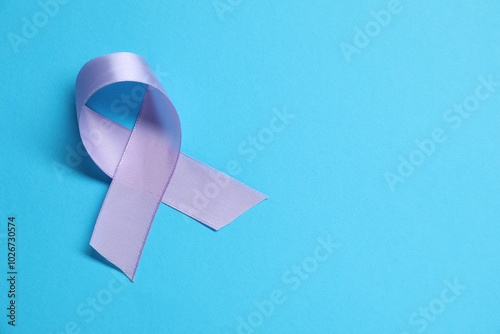 Violet awareness ribbon on light blue background, top view. Space for text photo