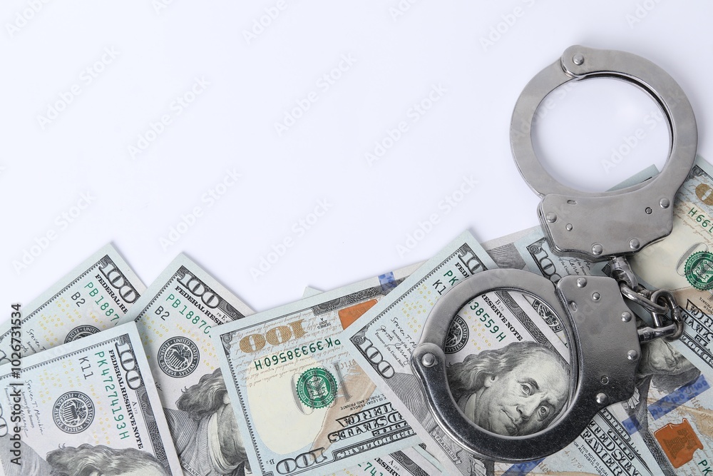 Corruption concept. Handcuffs and dollar banknotes on white background, top view Corruption concept. Handcuffs and dollar banknotes on white background, top view