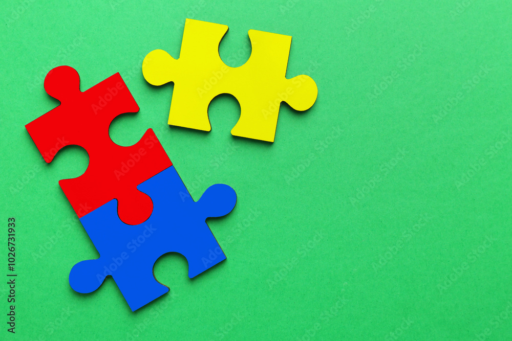 Fototapeta premium Three colorful puzzle pieces on green background, top view. Symbol of autism
