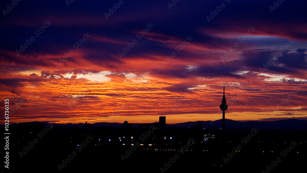 Fototapeta premium Panoramic view of the skyline of the city of Madrid at sunset with reddish tones and the profile of the piruli