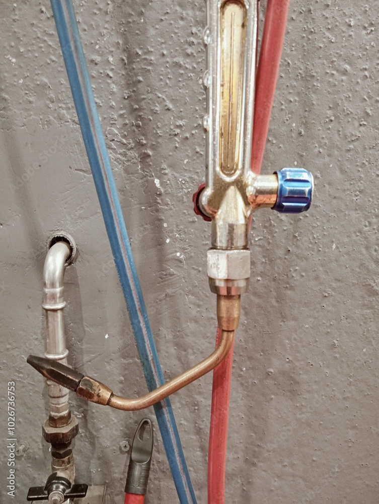 welding torch with pipes and pressure reducers on a workshop wall. Industrial equipment