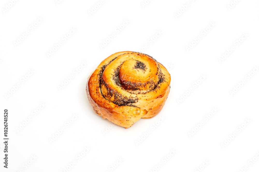 Cinnamon bun topped with poppy seeds. The roll is round and has a slightly browned crust. Cinnamon bun topped with poppy seeds. The roll is round and has a slightly browned crust.