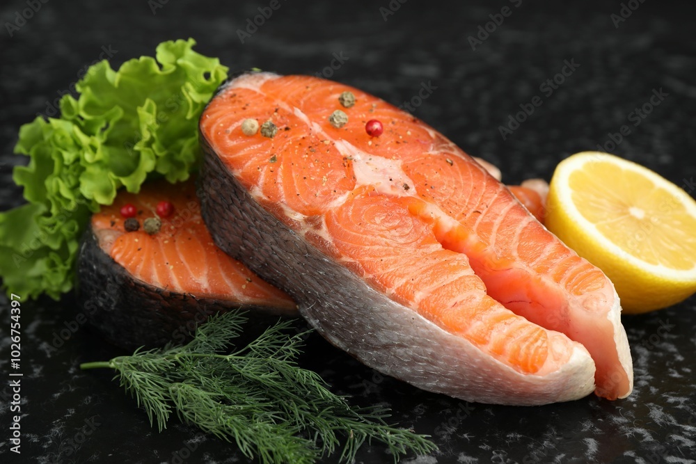 Fresh raw salmon steaks with spices, lemon, lettuce and dill on dark textured table, closeup Fresh raw salmon steaks with spices, lemon, lettuce and dill on dark textured table, closeup