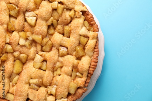 Tasty homemade apple pie on light blue background, top view. Space for text