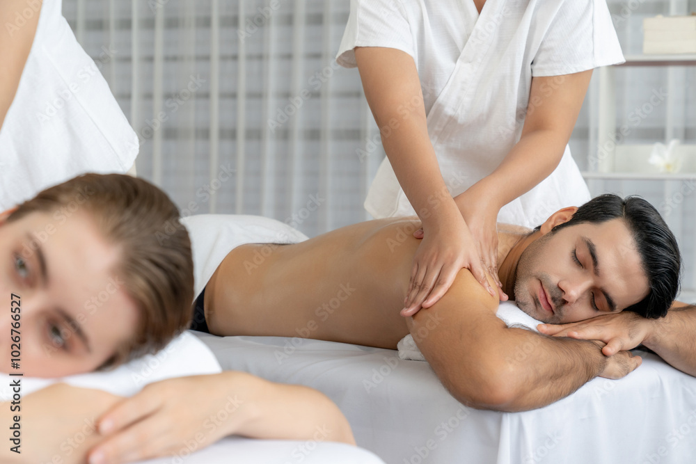 Caucasian couple customer enjoying relaxing anti-stress spa massage and pampering with beauty skin recreation leisure in day light ambient salon spa at luxury resort or hotel. Quiescent Caucasian couple customer enjoying relaxing anti-stress spa massage and pampering with beauty skin recreation leisure in day light ambient salon spa at luxury resort or hotel. Quiescent