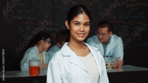 Tableau sur toile Girl looking at camera with arm folded while people doing experiment at laboratory