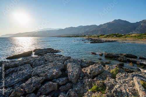 Empty rocky beach at sunset, clear blue sky, backlit, Greece, Crete island, wide angle lens