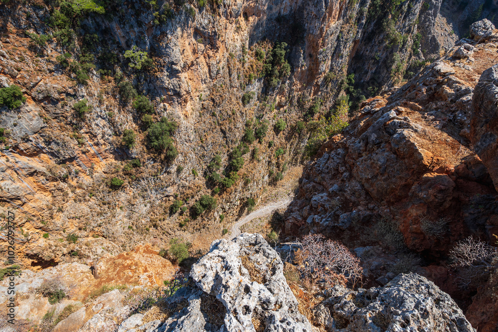 Narrow, steep, rocky valley from above, with small footpath at the bottom, in sunshine, Aradena gorge, Greece, island of Crete, wide angle lens Narrow, steep, rocky valley from above, with small footpath at the bottom, in sunshine, Aradena gorge, Greece, island of Crete, wide angle lens