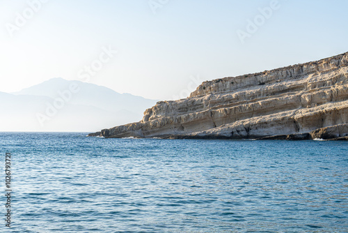 Φωτογραφία Stratified rock runs obliquely into the sea, clear blue sky, landscape, telephot