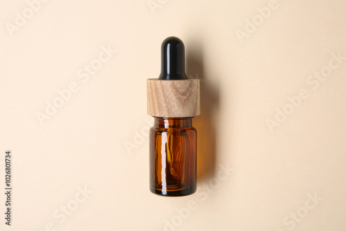 Essential oils in bottle on beige background, top view