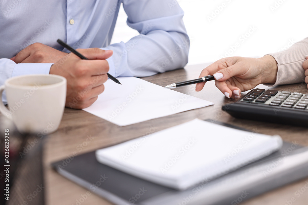 Banker working with client at wooden table in office, closeup Banker working with client at wooden table in office, closeup