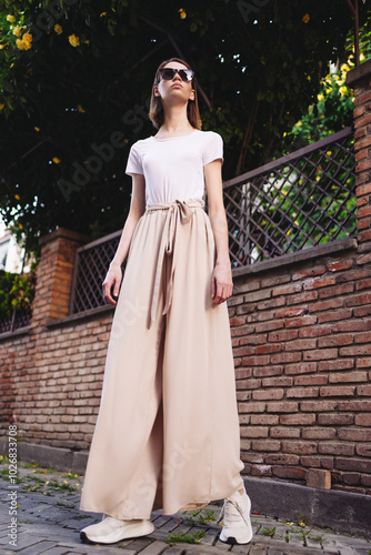 A young girl dressed in wide trousers and a hat walks through the old city.