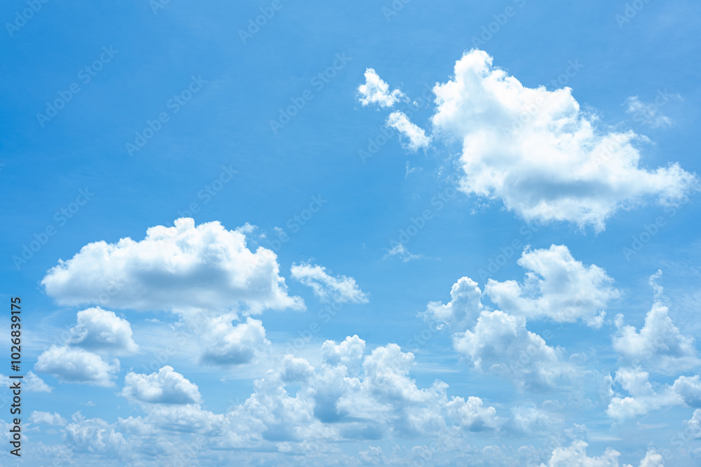 Fluffy white clouds drift across a bright blue sky, painting a beautiful summer landscape Fluffy white clouds drift across a bright blue sky, painting a beautiful summer landscape