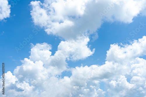 Fluffy cumulus clouds drift across a bright blue sky, painting a beautiful summer day