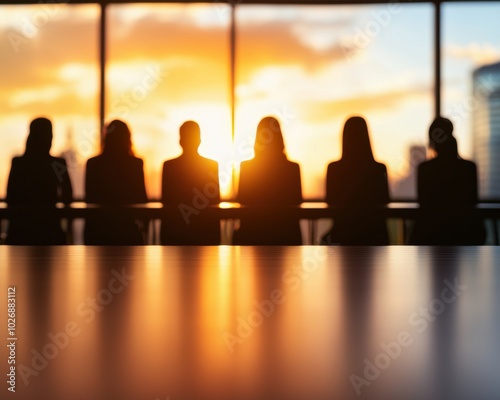 Silhouettes of people in a meeting against a sunset background.