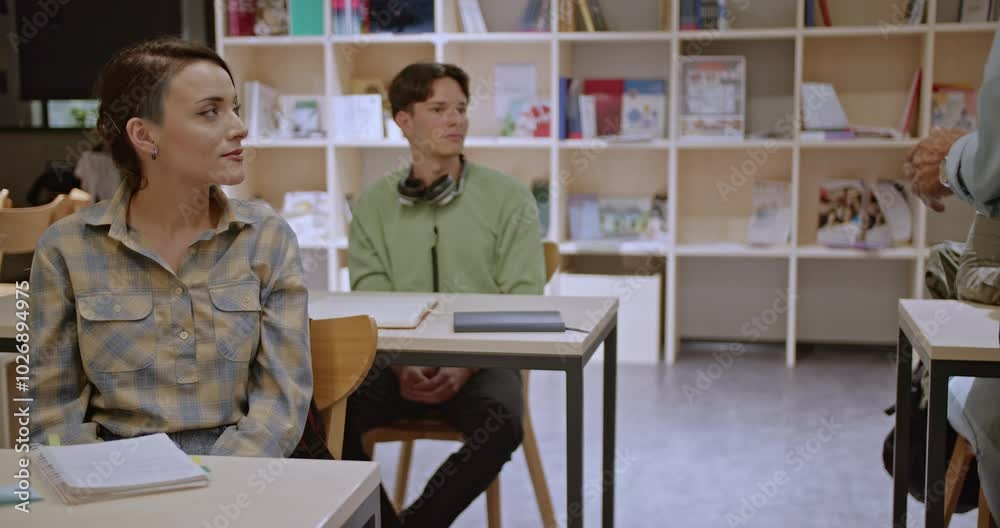 Focused university students working on their individual tasks in a modern library setting, receiving guidance from an elderly professor when needed.