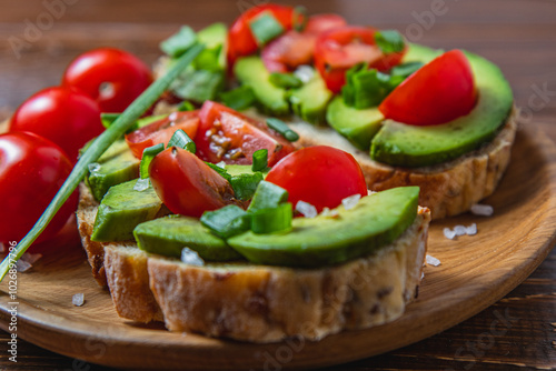 Avocado toast topped with tomato and green onion on a slice of carrot bread