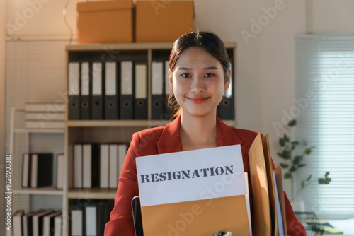 Young businesswoman is holding her resignation letter and smiling in the office photo