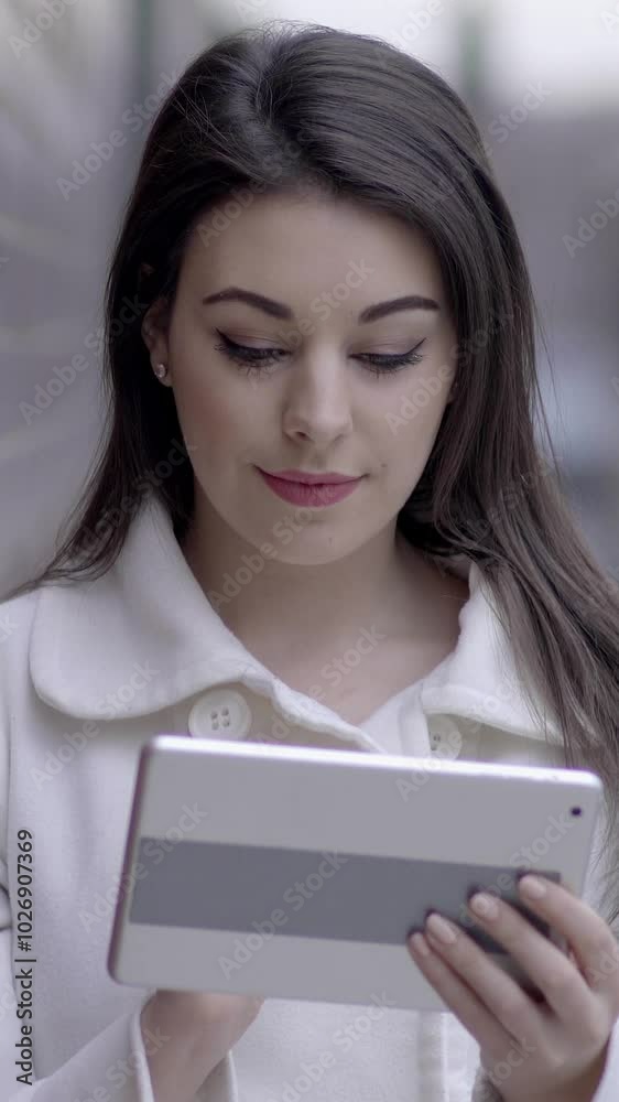 A focused young woman engages with her tablet in a lively urban setting full of activity A focused young woman engages with her tablet in a lively urban setting full of activity