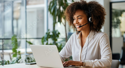Smiling african american woman, customer service representative working at desk with laptop.