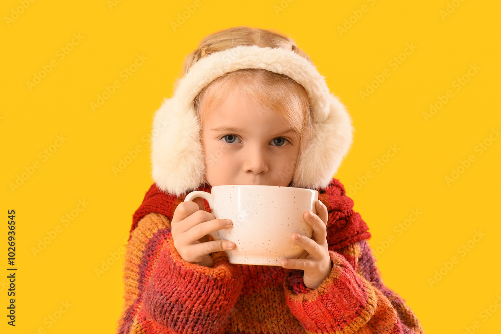 Cute little girl in winter clothes drinking cocoa on yellow background, closeup Cute little girl in winter clothes drinking cocoa on yellow background, closeup