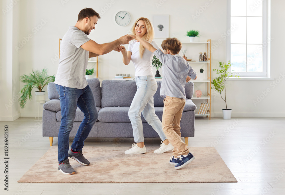 Mother, father, and little son enjoy leisure time dancing to music together at home. The happy family creates joyful memories while playing and bonding through active and fun activities. Mother, father, and little son enjoy leisure time dancing to music together at home. The happy family creates joyful memories while playing and bonding through active and fun activities.