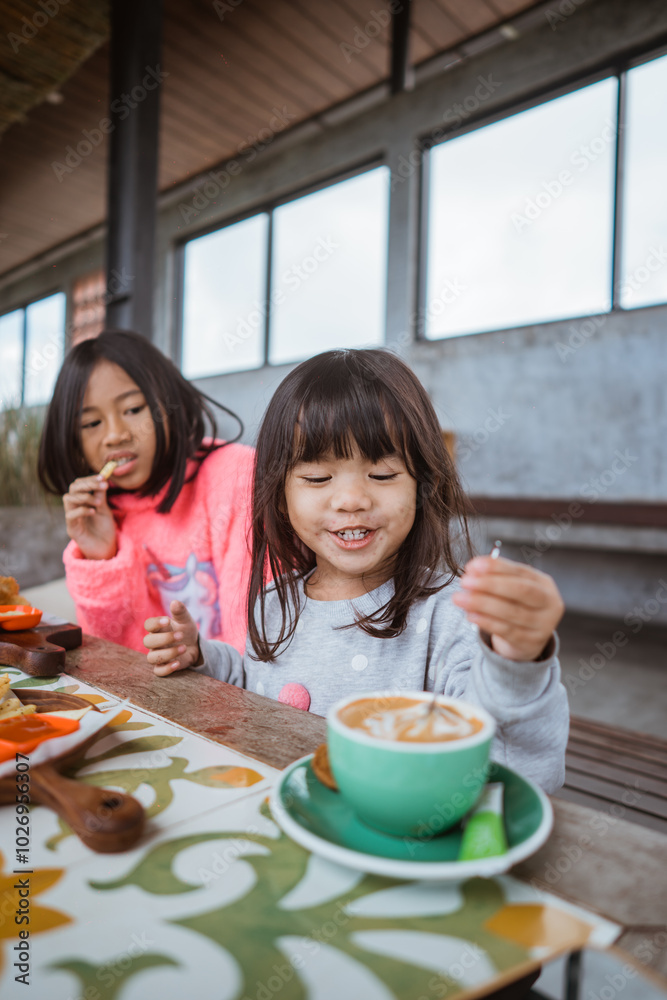 Two cheerful girls are sharing a delightful breakfast moment at a rustic wooden table Two cheerful girls are sharing a delightful breakfast moment at a rustic wooden table