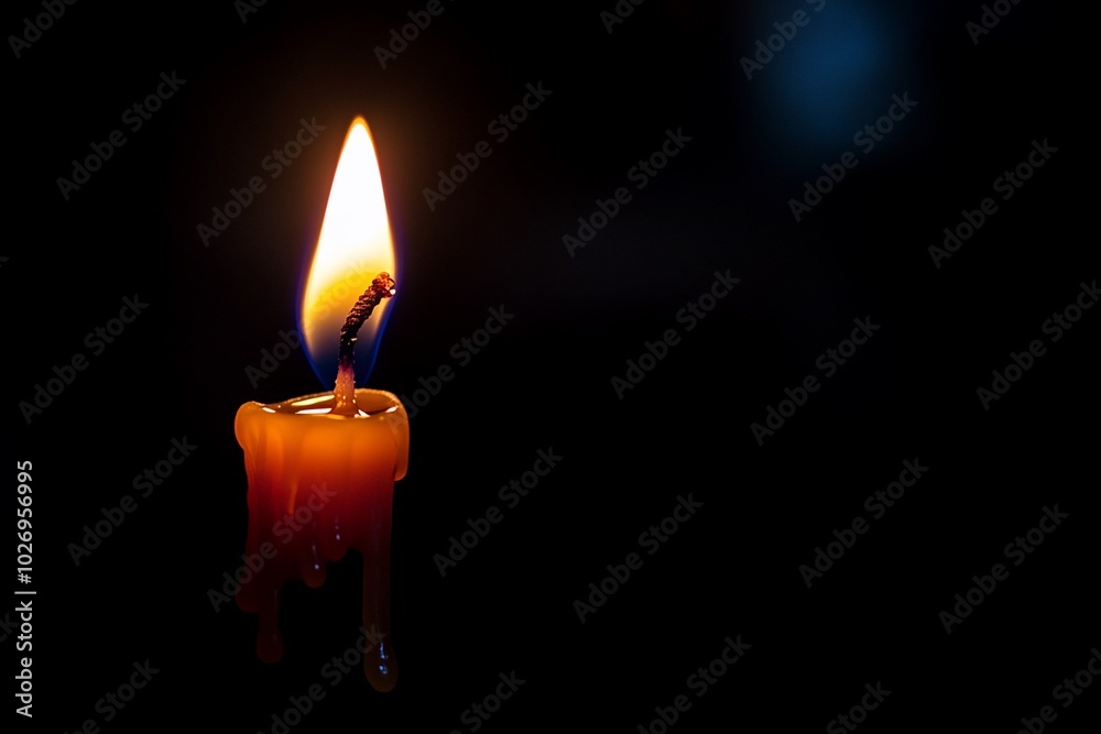 A single candle flame burning brightly against a dark background, with wax dripping down the side.
