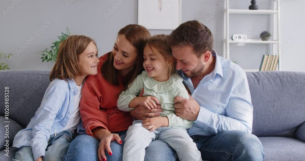Happy family portrait, friendly loving cheerful couple of parents and cute children on cozy sofa, enjoying family leisure at home smiling, laughing together, looking at camera, positive relationship Happy family portrait, friendly loving cheerful couple of parents and cute children on cozy sofa, enjoying family leisure at home smiling, laughing together, looking at camera, positive relationship