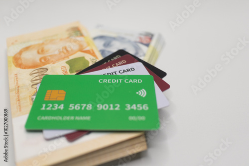 Green credit card placed on a stack of Singapore dollar banknotes, representing financial transactions, digital payments, and modern banking solutions .