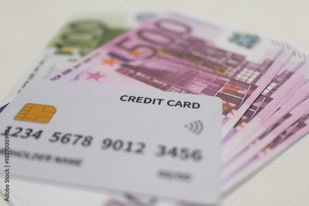 White credit card placed on a stack of purpleand greenEuro banknotes, symbolizing cashless payments, digital transactions, and European currency.