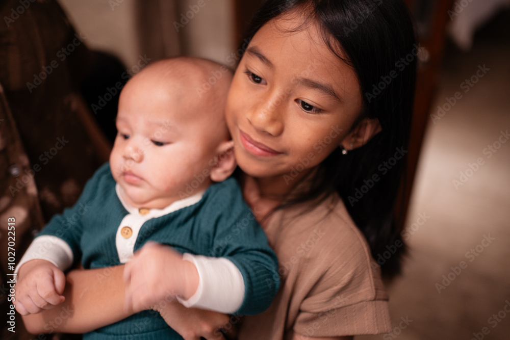 A young girl is gently and lovingly holding a small baby in her arms, showcasing a heartwarming moment of shared affection and care A young girl is gently and lovingly holding a small baby in her arms, showcasing a heartwarming moment of shared affection and care