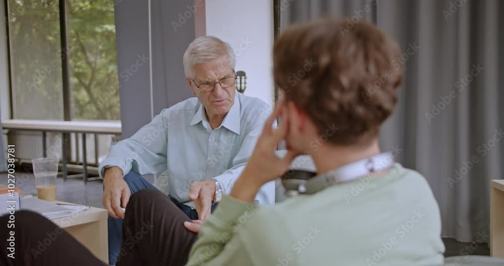 Two students, one older and one younger, having a discussion in a library. They are both smiling and happy while learning. Two students, one older and one younger, having a discussion in a library. They are both smiling and happy while learning.