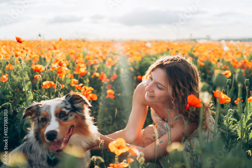 woman and her australian shepherd dog frolic in a vibrant poppy field