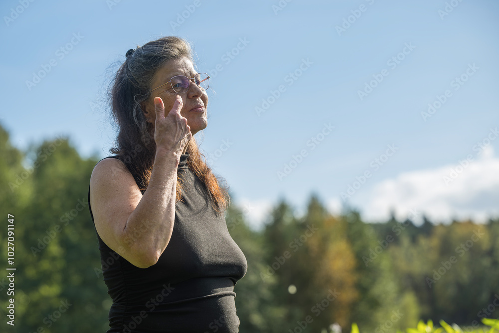 Eine ältere Frau streicht sich die Haare aus dem Gesicht