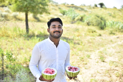 Young Boy with half a watermelon in her hands posing in a farmer field photo