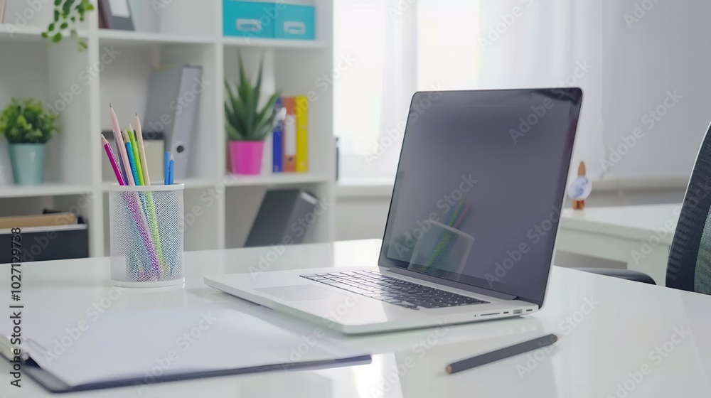 Front view laptop on white table. There is paper and a pen holder nearby. In modern office space Front view laptop on white table. There is paper and a pen holder nearby. In modern office space