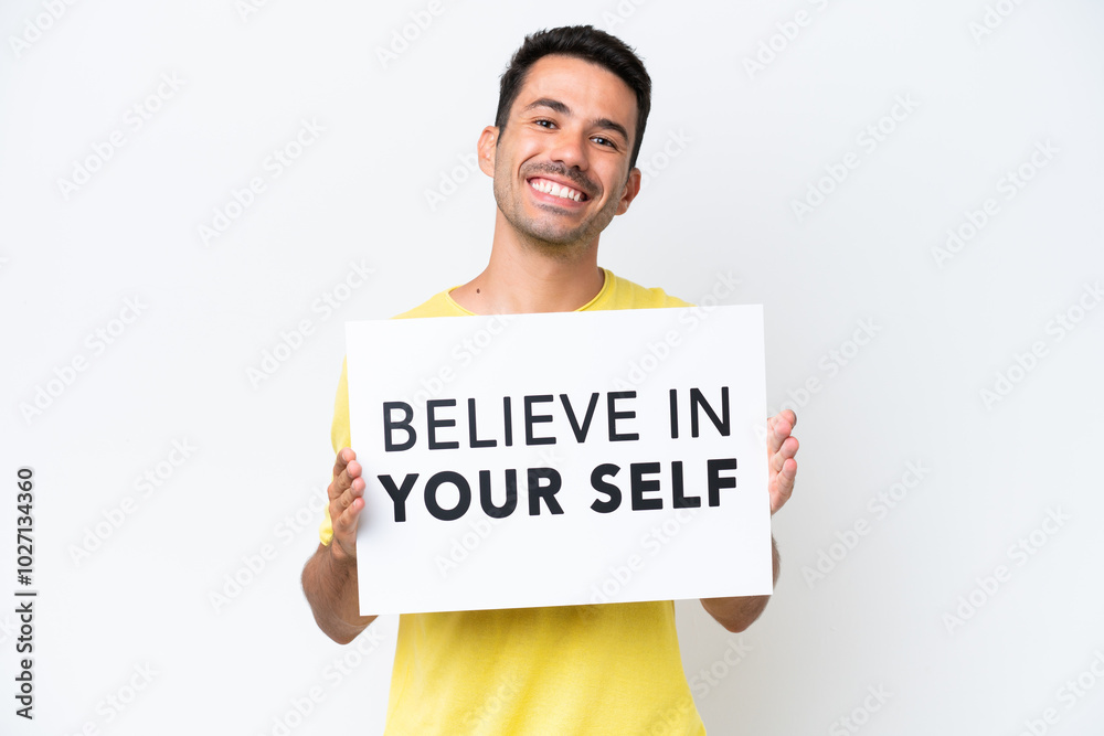 Young handsome man over isolated white background holding a placard with text Believe In Your Self with happy expression