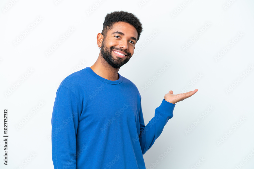 Young Brazilian man isolated on white background extending hands to the side for inviting to come Young Brazilian man isolated on white background extending hands to the side for inviting to come