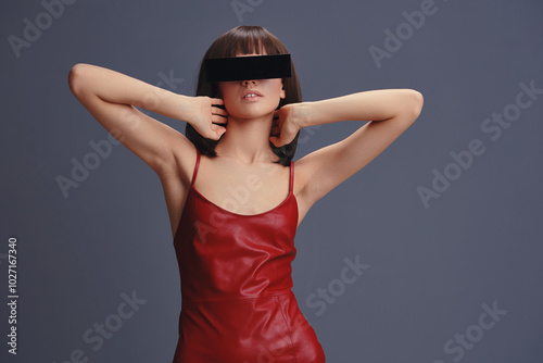 Canvas Print A woman in a red leather dress with a blindfold over her eyes and hands on her h