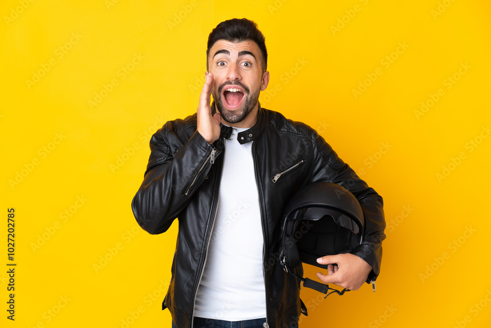 Caucasian man with a motorcycle helmet over isolated yellow background with surprise and shocked facial expression Caucasian man with a motorcycle helmet over isolated yellow background with surprise and shocked facial expression