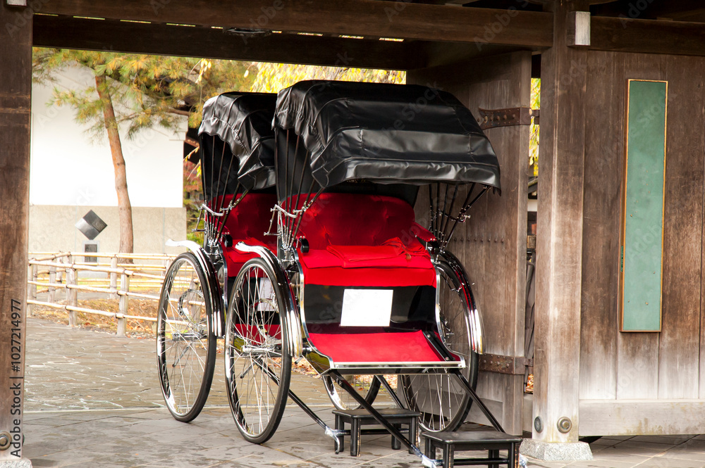 Obraz premium Red coloured seat rickshow parked under a wooden gate